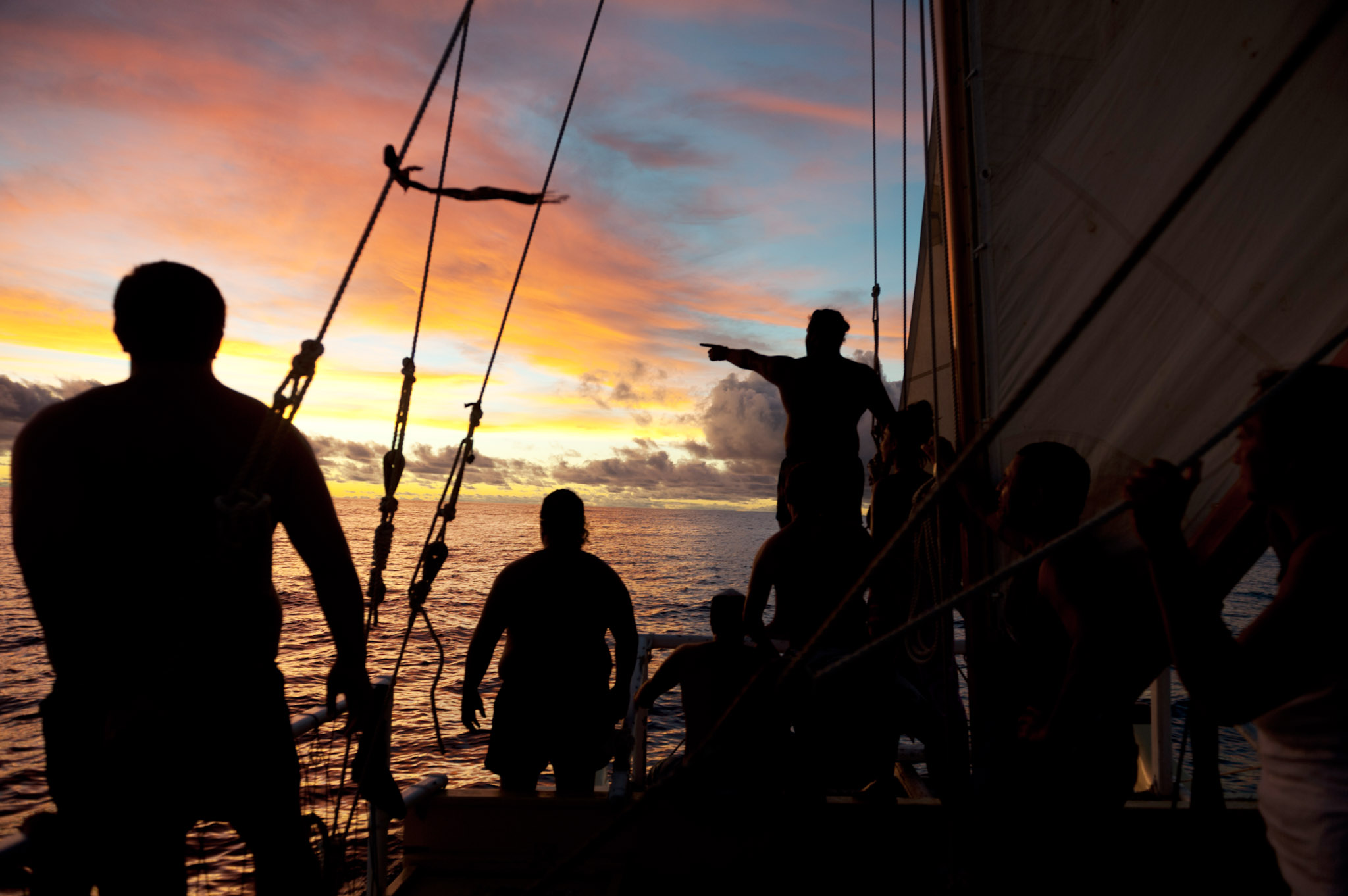 Crew onboard a Polynesian voyaging canoe at dusk